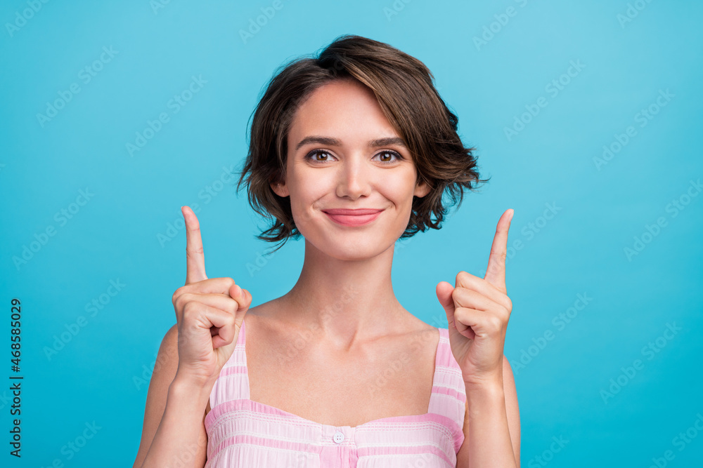 Photo of lovely young promoter lady directing up wear pink top isolated on blue color background Photo of lovely young promoter lady directing up wear pink top isolated on blue color background