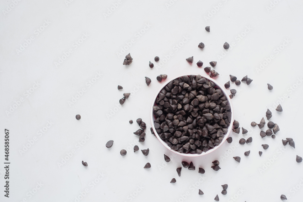 Chocolate chips in a container on white background Chocolate chips in a container on white background