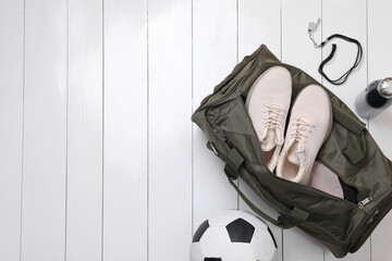 Gym bag and sports equipment on white wooden background, flat lay. Space for text
