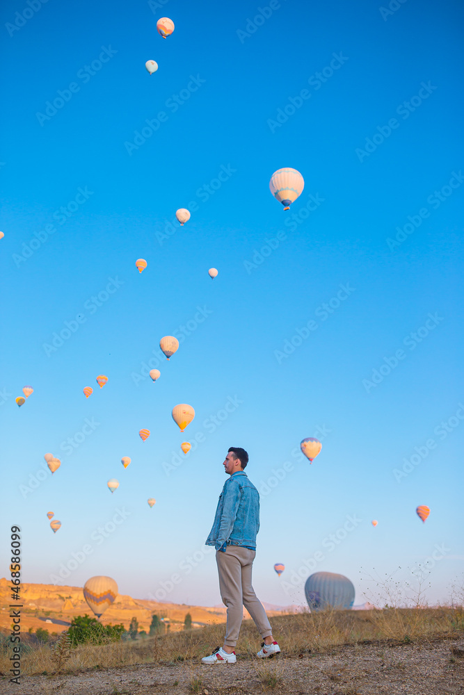Happy man during sunrise watching hot air balloons in Cappadocia, Turkey Happy man during sunrise watching hot air balloons in Cappadocia, Turkey