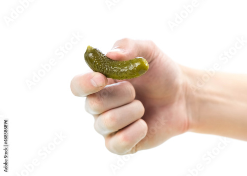 The hand holds a small pickle. Isolated on a white background