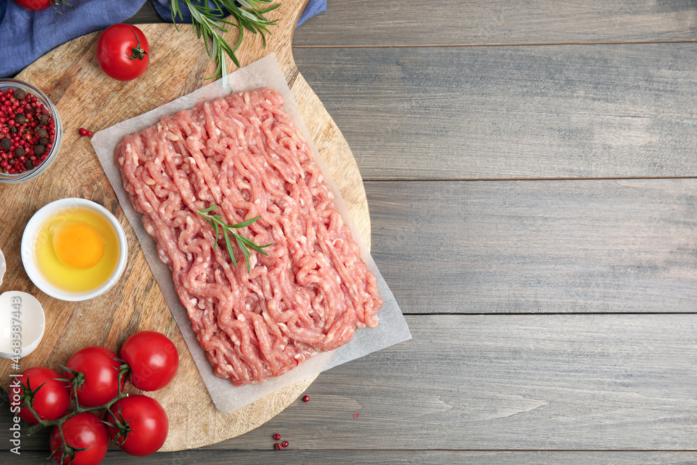 Raw chicken minced meat and ingredients on grey wooden table, flat lay. Space for text