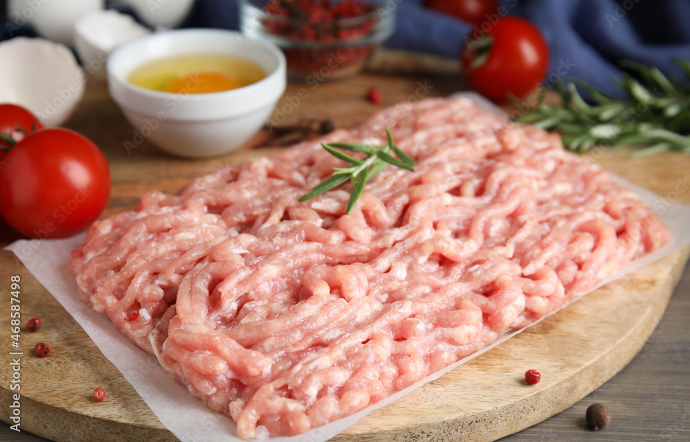 Raw chicken minced meat with rosemary on grey wooden table, closeup Raw chicken minced meat with rosemary on grey wooden table, closeup