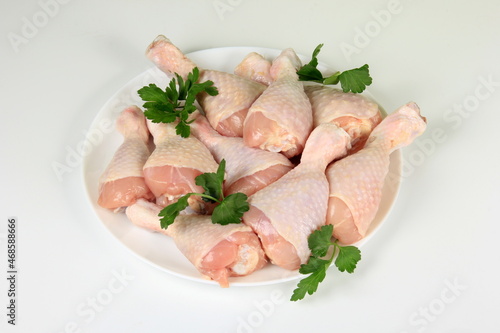 Raw Chicken legs on a white plate, white background
