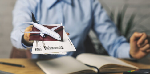 travel agent with flight tickets and plane model in hand at agency office. tourism service. copy space