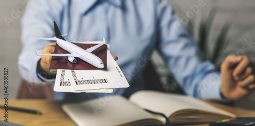 travel agent with flight tickets and plane model in hand at agency office. tourism service. copy space photo