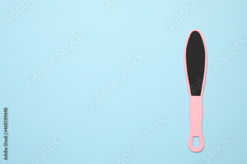 Pink foot file on light blue background, top view with space for text. Pedicure tool