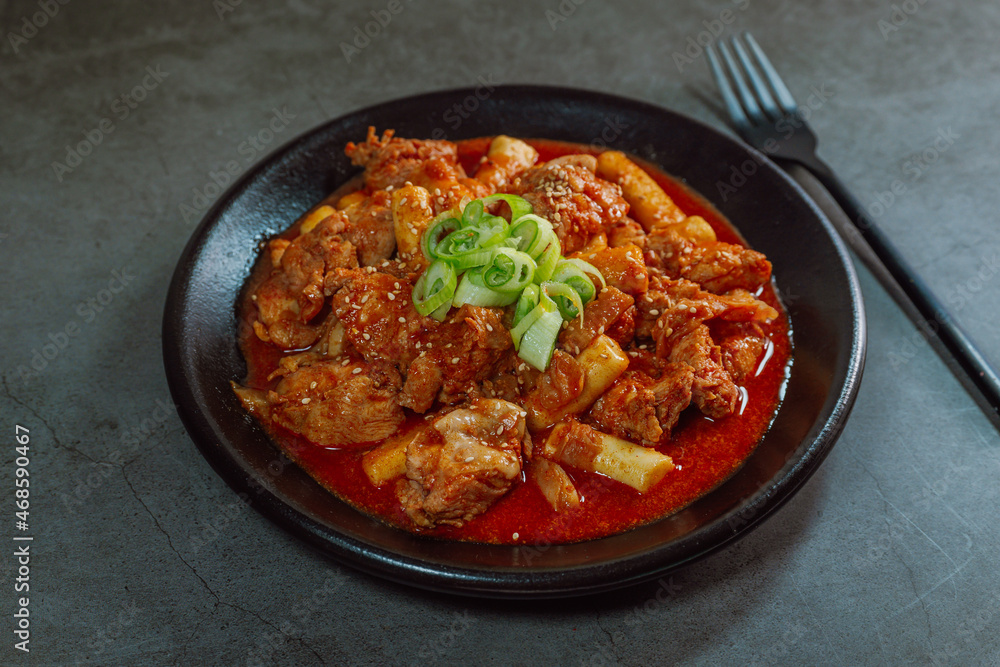 Korean food Spicy Stir-fried Chicken tteokbokki dish on black plate Korean food Spicy Stir-fried Chicken tteokbokki dish on black plate