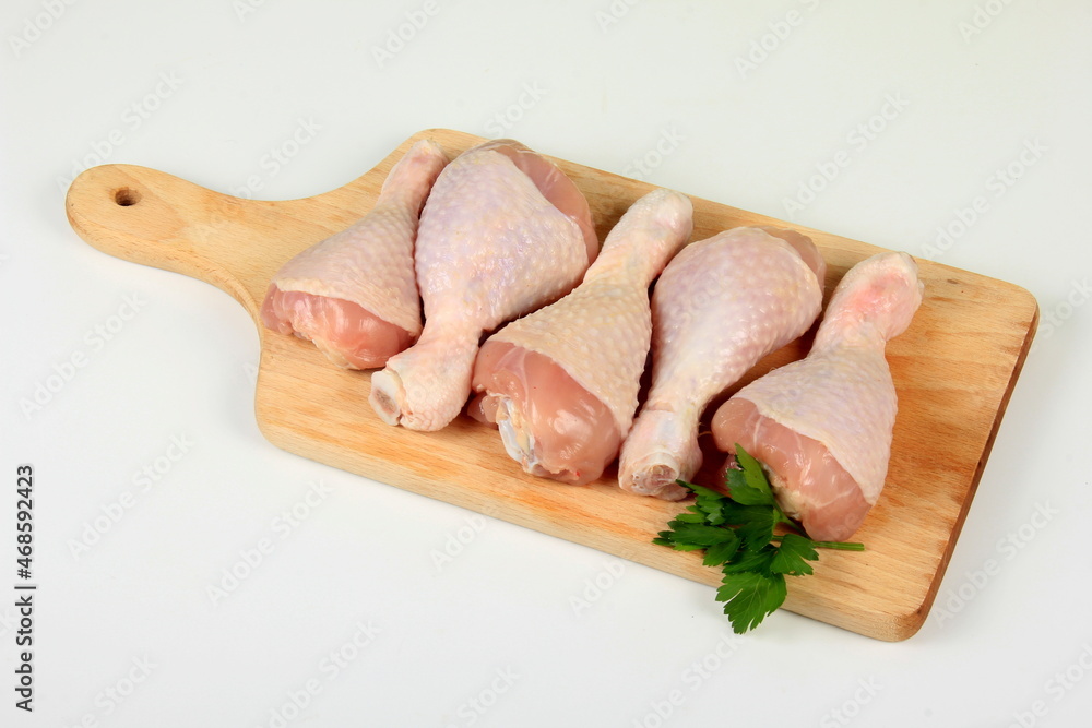 Fresh chicken drumsticks on wooden board isolated on white. Group of Raw Chicken legs isolated on white background 