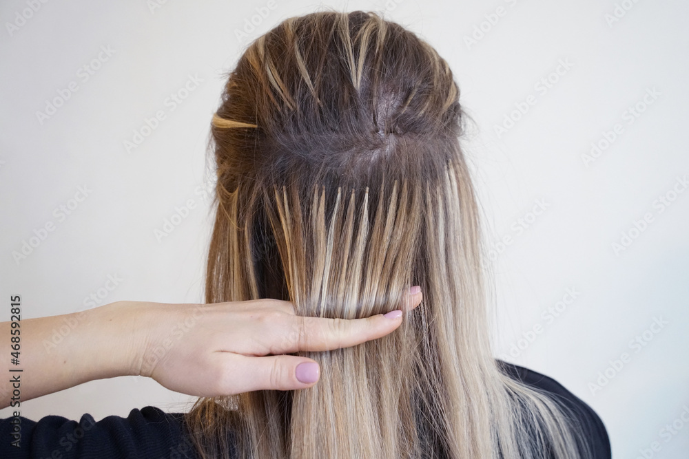 Obraz premium Natural Hair extensions blonde woman on a white background. Close up of capsules from back