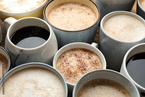 Many cups of different coffees on table, closeup photo