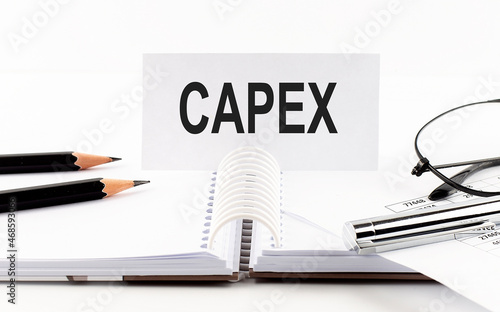 Text CAPEX on paper card,pen, pencils, glasses,financial documentation on table - business concept