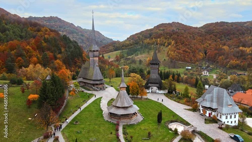 Aerial drone view of the Barsana Monastery, Romania. Main church and other buildings, visitors, hills covered with yellowing forest around