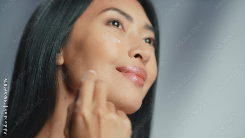 Beautiful Asian Woman Gently Touching Her Face. Young Female with Lush Black Hair Makes Her Skin Soft. Abstract Concept Natural Cosmetics Skincare Product. Stylish Portrait Isolated Gray Background Beautiful Asian Woman Gently Touching Her Face. Young Female with Lush Black Hair Makes Her Skin Soft. Abstract Concept Natural Cosmetics Skincare Product. Stylish Portrait Isolated Gray Background