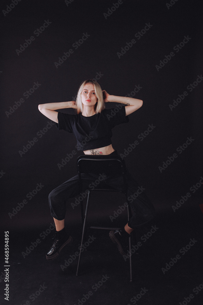 blonde girl in the studio on a black background in black clothes