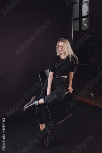 blonde girl in the studio on a black background in black clothes