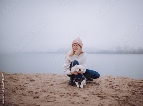 a girl on an autumn beach walks with a Pekingese dog, a foggy morning © Наталья Ржевская