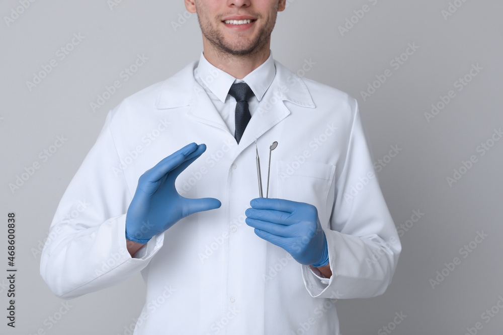 Dentist holding tools on light grey background, closeup Dentist holding tools on light grey background, closeup