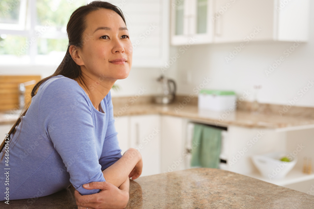 Portrait of happy asian woman sitting at table in kitchen Portrait of happy asian woman sitting at table in kitchen