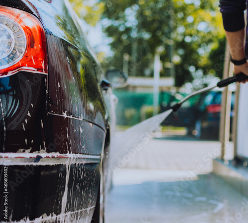 the guy washes the car in the self-service car wash