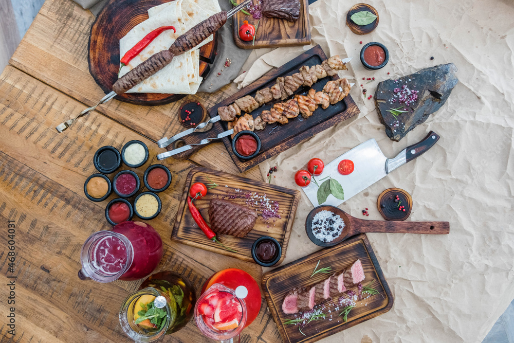 Flat composition with fried meat, shish kebab, steak, lula kebab and vegetables on a wooden table Flat composition with fried meat, shish kebab, steak, lula kebab and vegetables on a wooden table