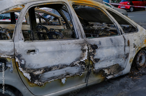 Burnt car's door in the street close-up. Riot, civil protest, hooliganism, criminal in the city. Explosion, fire result. Car insurance concept 