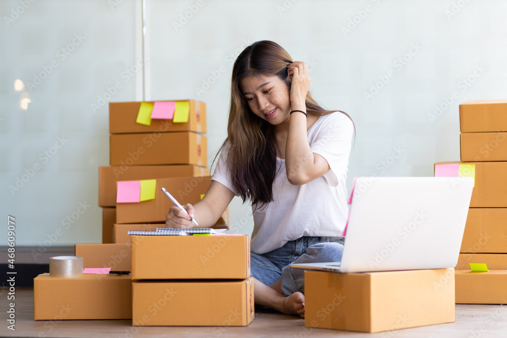 A young woman owning a small business online marketing is writing a record of orders from customers. A young woman owning a small business online marketing is writing a record of orders from customers.