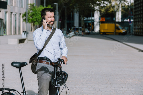 Well dressed man with bicycle talking on smartphone photo