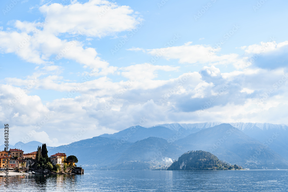 Coast of the town of Varenna against the backdrop of mountains and blue sky. Como, Italy