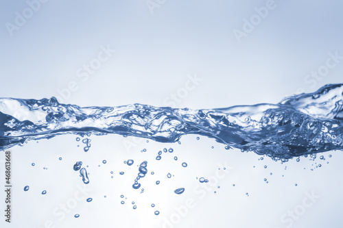 Water splash on blue background. Aqua flowing in waves and creating bubbles. Drops on the water surface feel fresh and clean.