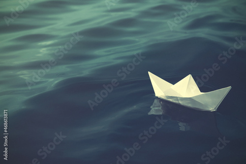 White paper boat floating on river. Retro photo effect