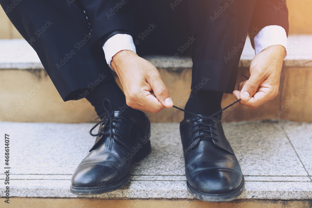 Close up of businessman hand tie shoelaces wearing leather shoes sitting on staircase background. Close up of businessman hand tie shoelaces wearing leather shoes sitting on staircase background.