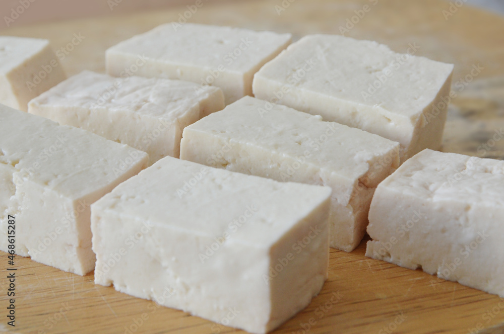Close up photo of fresh made tofu cubes on a wooden cutting board