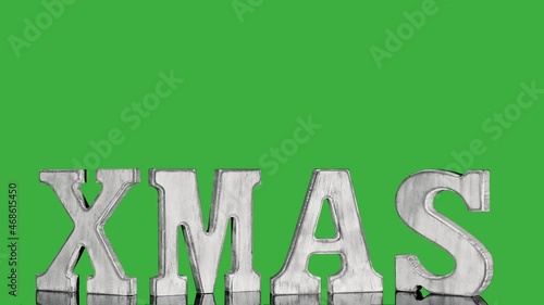 Wooden christmas letters XMAS in vintage style rotate on green screen