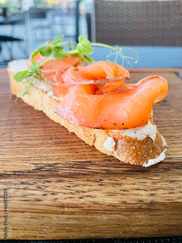 bruschetta with salad, salmon and cottage cheese on a craft wooden board