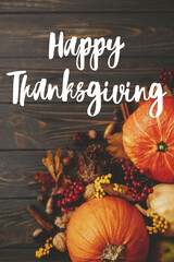 Happy Thanksgiving Card. Happy thanksgiving text on pumpkins, autumn leaves, anise, berries, acorns border on rustic wood flat lay. Season's greetings, handwritten lettering. Give thanks
