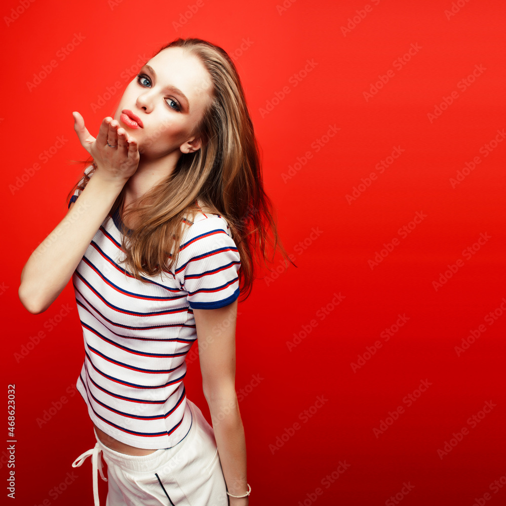 Naklejka premium young pretty emitonal posing teenage girl on bright red background, happy smiling lifestyle people concept