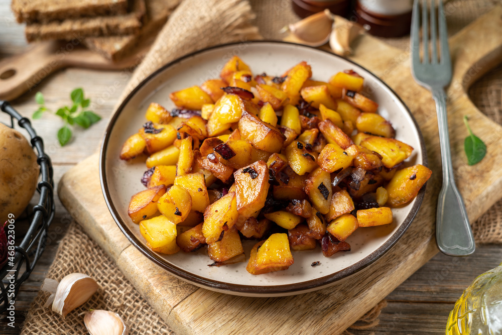 Fried potatoes in a plate on a gray wooden table closeup Fried potatoes in a plate on a gray wooden table closeup