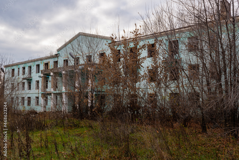 An old ruined dormitory overgrown with trees. An empty dormitory, intended for demolition. An ordinary crumbling building, in an unusual place in Russia.