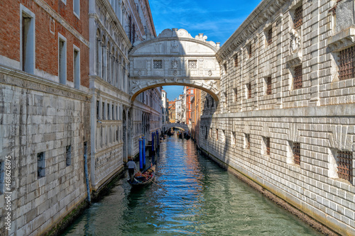 gondola with tourists travelling through the narrow canals of the old town of Venice