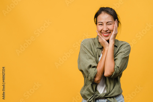 Young Asia lady with positive expression, smile broadly, dressed in casual clothing and looking at camera over yellow background. Happy adorable glad woman rejoices success. Facial expression concept. © tirachard