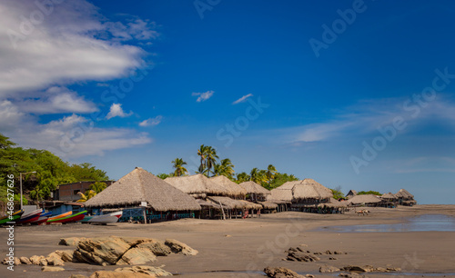 Thatched roof restaurants near the beach, thatched roof restaurant near wooden boats with blue sky, nicaragua restaurants near the beach