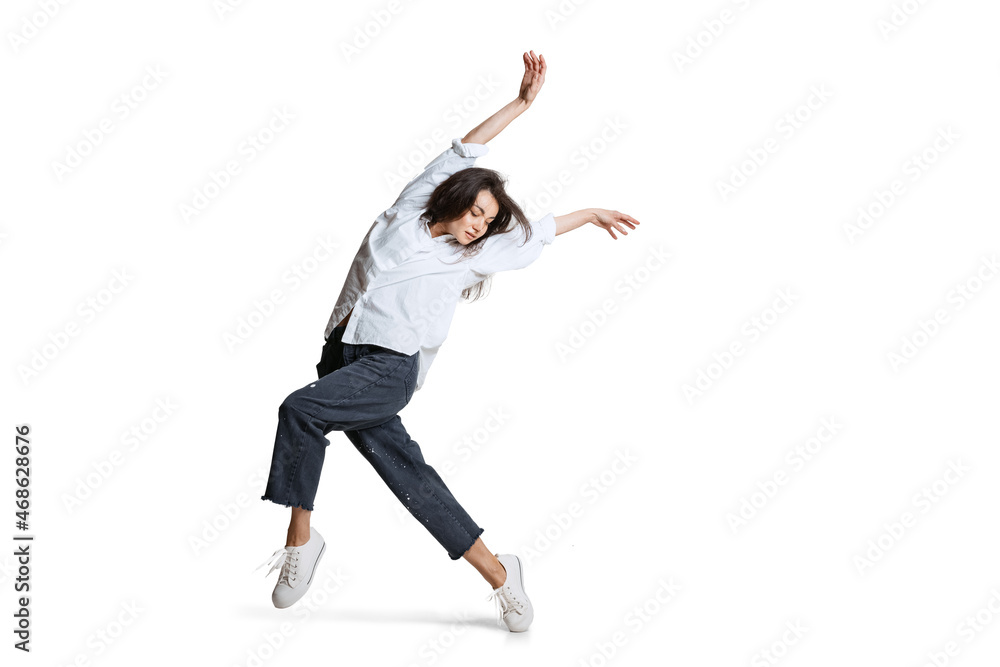 Young woman in casual wear moves dynamically isolated on white background. Art, motion, action, flexibility, inspiration concept.