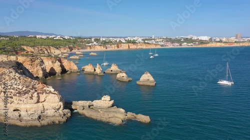 Aerial view, drone footage, of Alemao Beach, Vao, the Portuguese Algarve coast and holidaymakers. Yachts and catamaran in the foreground. photo