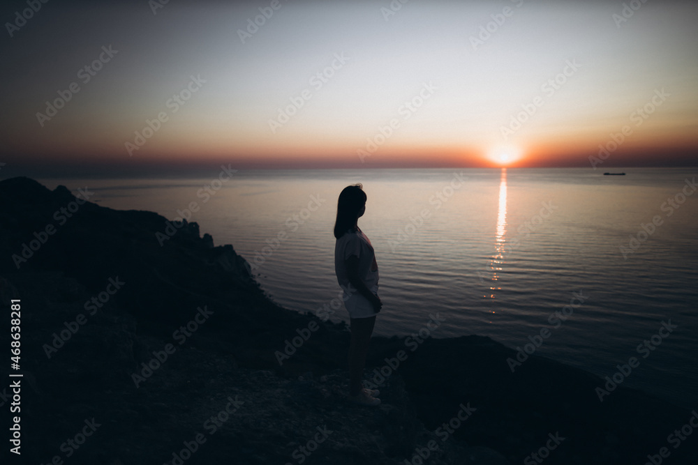 Silhouette of a girl on the background of the sea during sunset Silhouette of a girl on the background of the sea during sunset