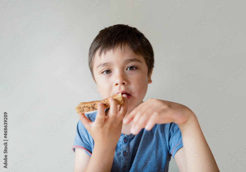 Portrait healthy Child boy eating honey on toasted for his breakfast before go to school, Happy kid child eating butter on bread in the morning, Healthy food for children concept