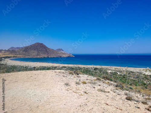 beautiful scene of a calm sea  under a blue sky with clouds and surrounded by a mountain with vegetation.