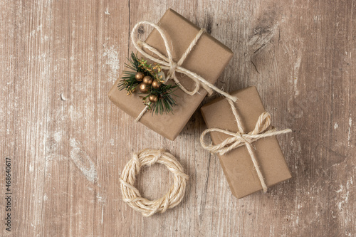 gift boxes wrapped in paper with a lace bow and a small ornament, wooden textured background, texture detail in studio, celebration wallpaper