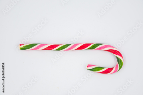 Festive Christmas treat. Flat lay of striped red candy cane isolated on white background. Copy space. #468641494