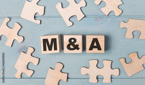 Blank puzzles and wooden cubes with the text M AND A lie on a light blue background.